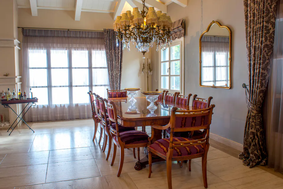 Dining room with a long wooden table, a chandelier and tall windows