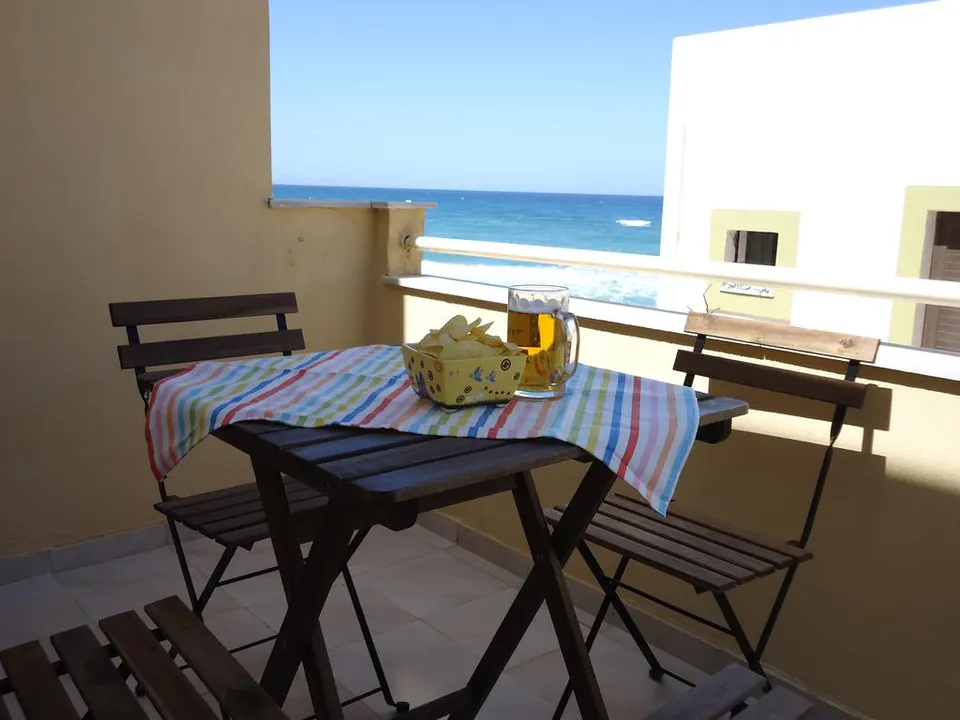 Table and chairs on the balcony, with the sea beyond the railing