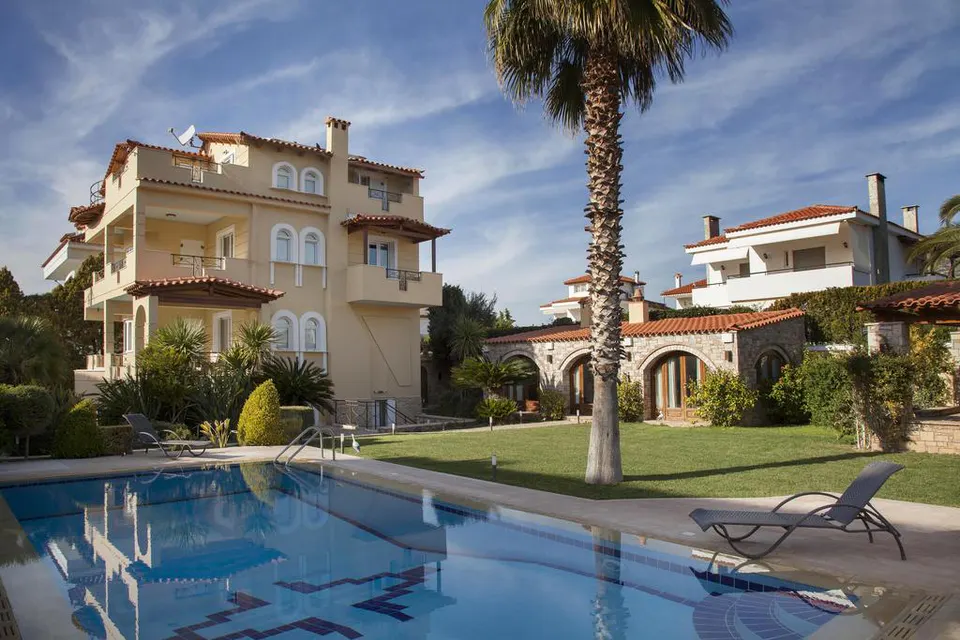 The villa seen across the swimming pool, with a palm tree and a lawn
