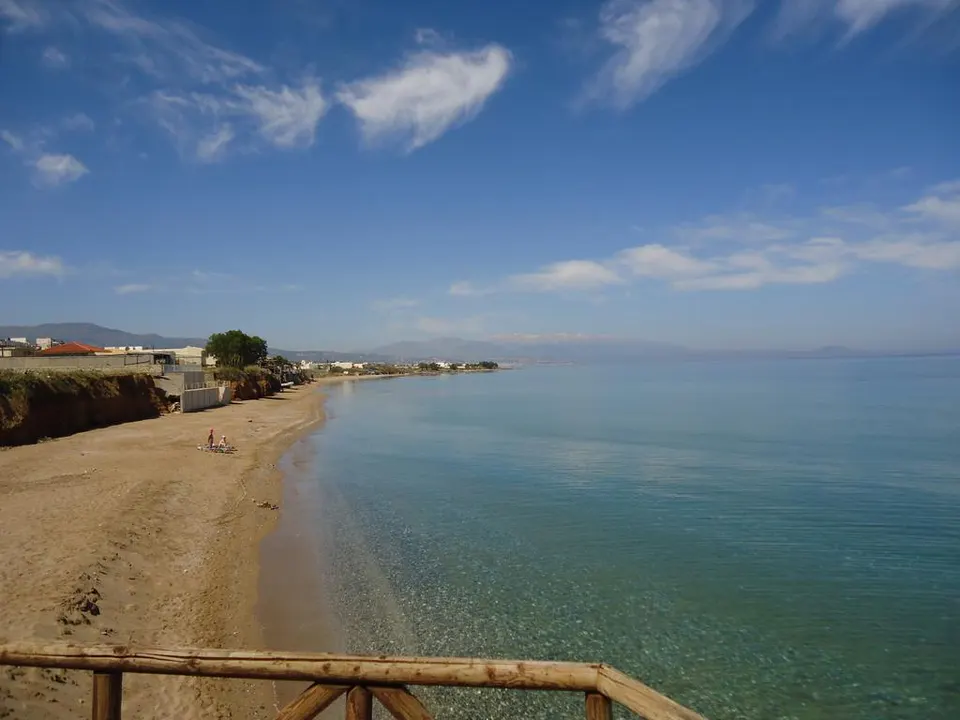 Sandy beach and clear sea seen from a wooden railing