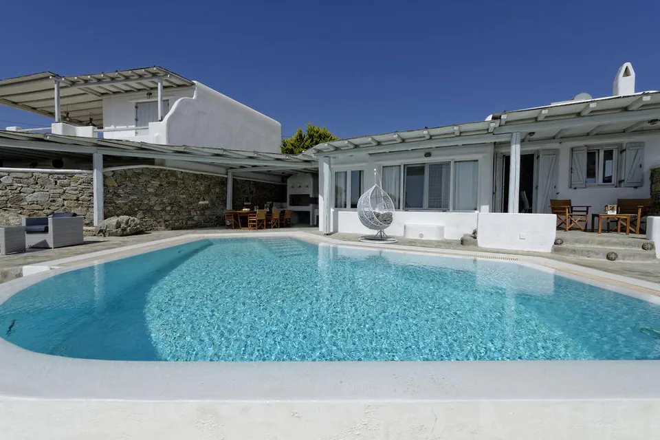 Pool in front of the villa, with a hanging chair and a pergola