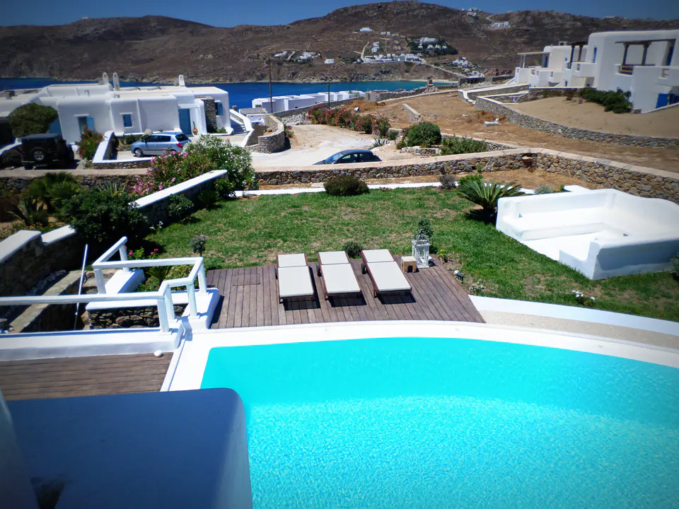 Pool, deck and garden seen from above, with the sea beyond