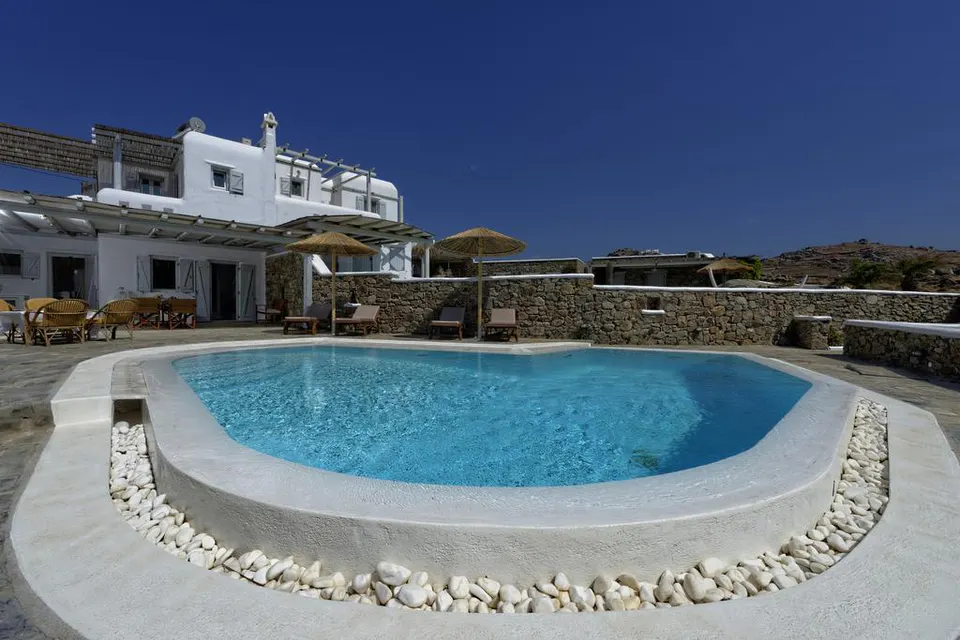 Pool with a white stone edge in front of the villa