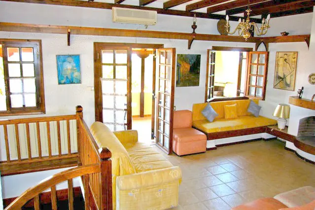 Living room with yellow sofas, a built-in bench, French doors and a wooden stair railing