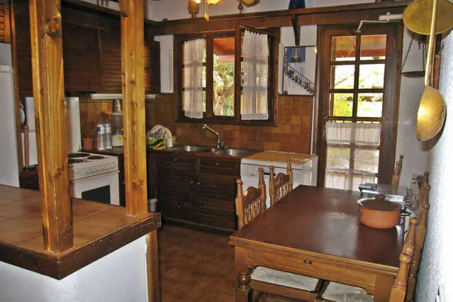 Kitchen with wooden cabinets, a hob, a sink and a dining table with chairs