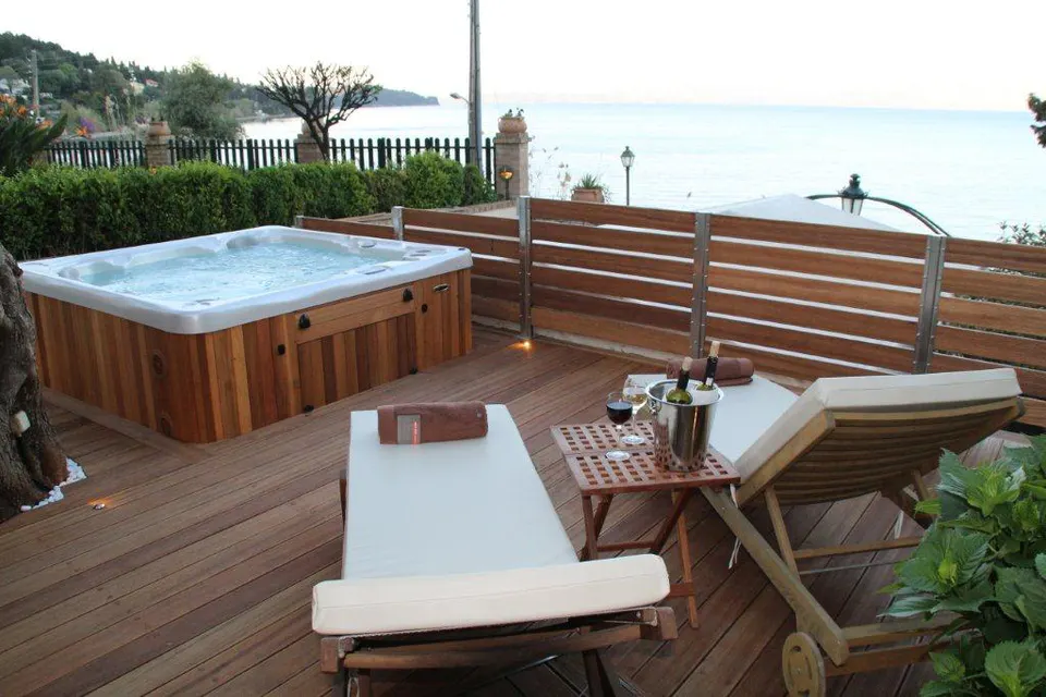 Hot tub and sun loungers on the wooden deck, the sea beyond