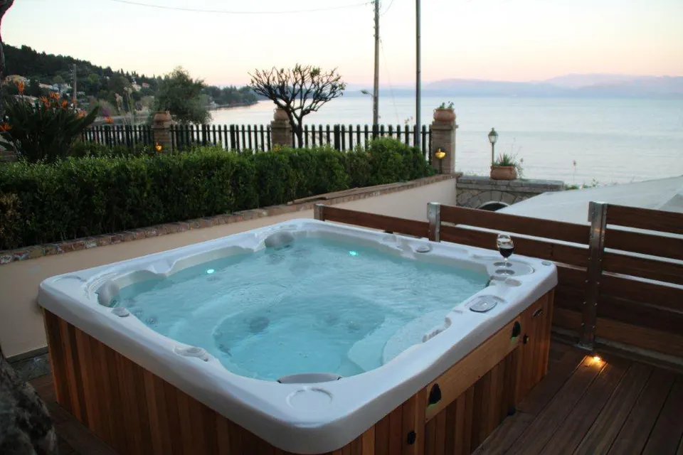 Hot tub with the deck lights on, the sea behind