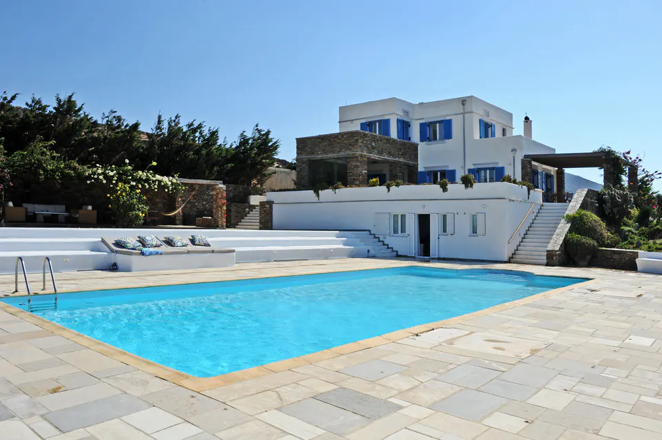Pool in front of the white house with blue shutters