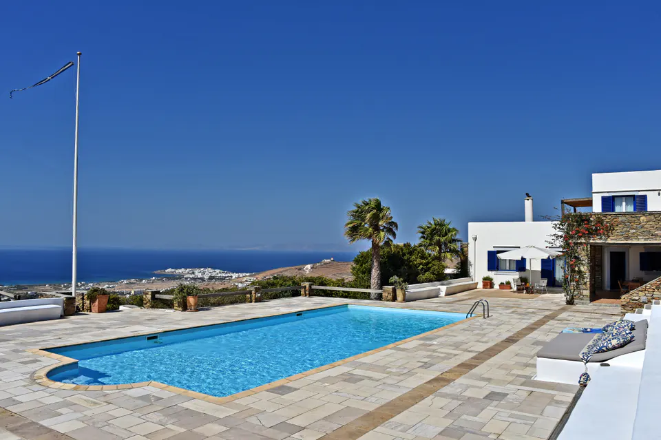 Pool terrace with a flagpole and a view over the sea and the coast